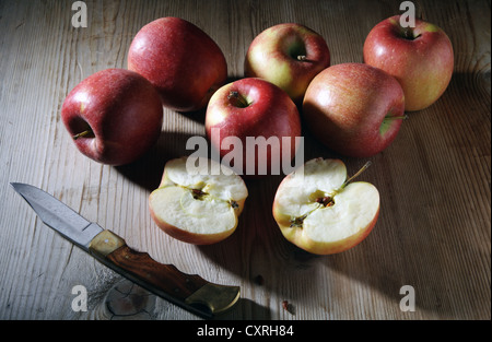 Diverse le Braeburn mele (malus domestica) con un coltello su un rustico di una superficie di legno Foto Stock