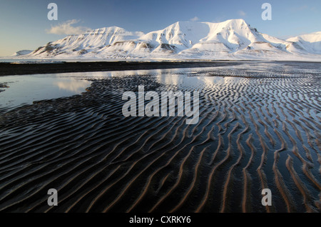 Hjorthfjellet, la montagna di casa di città di Longyearbyen, si riflette nel fango invernale appartamenti, Spitsbergen, Svalbard, Norvegia Foto Stock