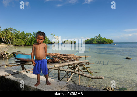 Ragazzo di Papua in piedi di fronte ad una laguna sull isola di Biak, fuori dell'isola di Papua Nuova Guinea, Indonesia Asia sud-orientale, Asia Foto Stock