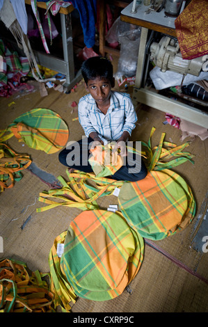 Il ragazzo, circa 13 anni, cucito insieme i cuscini colorati in casa sua, Karur, Tamil Nadu, India meridionale, India, Asia Foto Stock