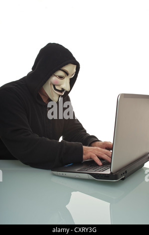 Uomo che indossa un 'Anonimo', Guy Fawkes o 'V per Vendetta" maschera, lavorando su un computer portatile Foto Stock