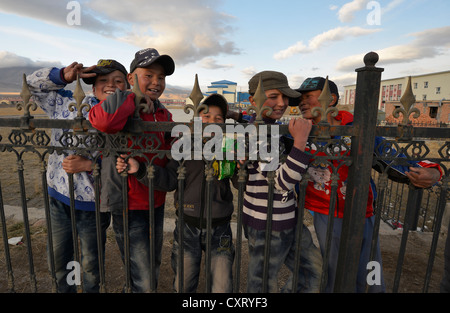 Il mongolo ragazzi con i cappelli da baseball in piedi dietro una recinzione di una scuola, Bayanbulak, Bayingolin mongolo prefettura autonoma, Kuqa Foto Stock