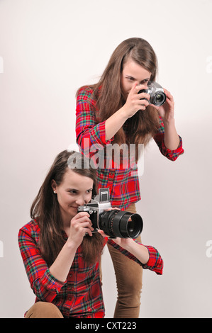 Gemelle holding telecamere, uno tenendo un Pentacon sei medio formato telecamera analogica, l'altra azienda una fotocamera digitale Foto Stock