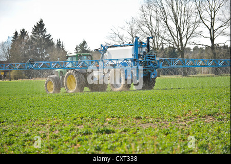 Agricoltore in un trattore la spruzzatura weed killer su un campo Foto Stock