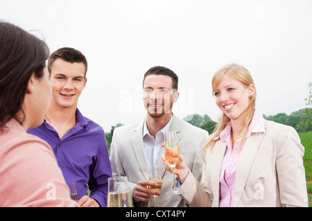 Un gruppo di giovani chinking occhiali, celebrando su un terrazzo Foto Stock