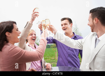 Un gruppo di giovani chinking occhiali, celebrando su un terrazzo Foto Stock