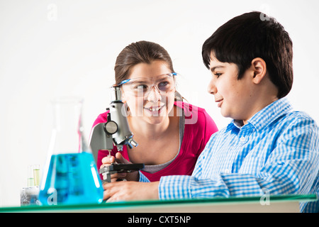 Un ragazzo e una ragazza davanti a un microscopio Foto Stock