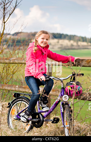 Ragazza con la bicicletta in parte anteriore del paesaggio rurale Foto Stock