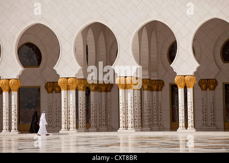 Adoratore di fronte i colonnati nella Moschea Sheikh Zayed di Abu Dhabi, Emirati Arabi Uniti, Asia Foto Stock