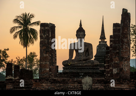 Silhouette di un Buddha seduto statua al crepuscolo, Wat Mahathat tempio, Sukhothai Historical Park, Patrimonio Mondiale dell UNESCO Foto Stock