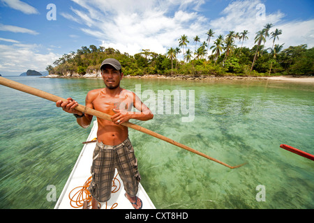 Boatsman in una tradizionale barca outrigger sulla partenza da Snake Isola Arcipelago Bacuit, El Nido, PALAWAN FILIPPINE Foto Stock