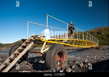 Femmina di escursionisti a piedi su un ponte mobile attraverso il glaciale Krossá river, sentiero escursionistico al Fimmvoerðuháls alta pianura Foto Stock