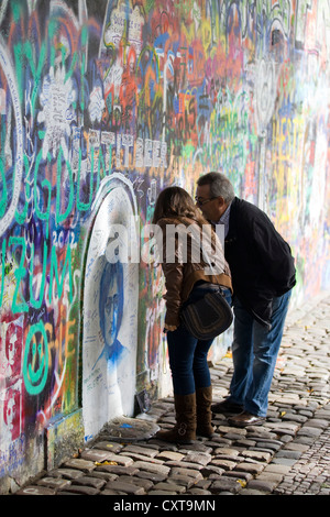 L uomo e la donna la lettura dei graffiti sul muro di John Lennon a Praga Foto Stock