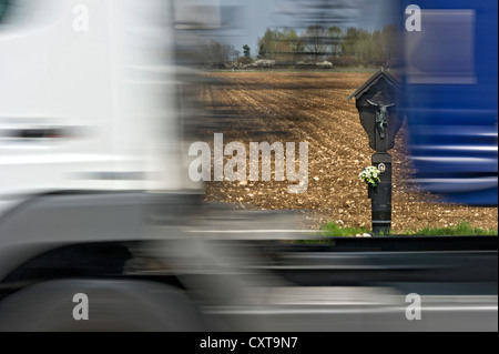 Commemorative croce sul ciglio della strada per la vittima di un incidente, con carrello velocizzando il passato, country road vicino a Anzing, Alta Baviera, Baviera Foto Stock