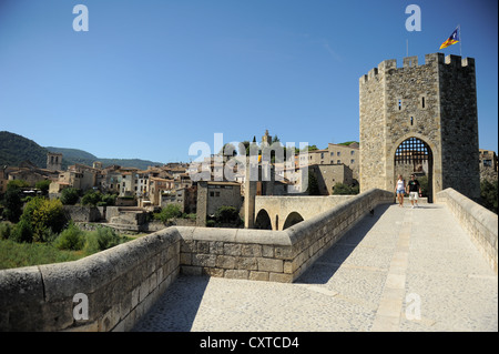 I turisti attraversando a piedi ponte fortificato oltre il fiume Fluvia nella città medievale di Besalu, Catalogna, Spagna Foto Stock