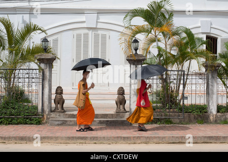 Due monaci passano da un edificio in stile coloniale Francese. Luang Prabang, Laos Foto Stock