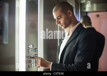 Imprenditore premendo il pulsante di ascensore Foto Stock