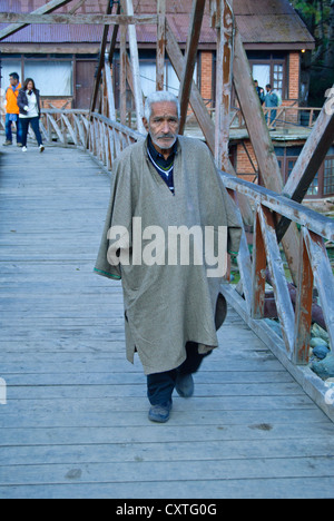 Un uomo a piedi attraverso un ponte in legno Pahalgam Foto Stock