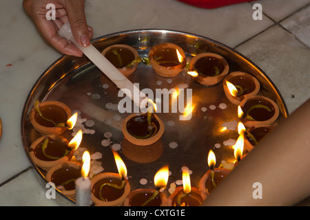 Quasi tutte le lampade ad olio illuminato da una candela come parte delle celebrazioni di Diwali. Questi sono stati mantenuti su una piastra e illuminato attraverso una candela. Foto Stock