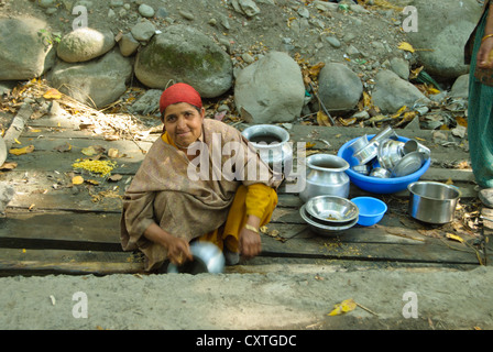 Un abitante locale lavaggio piatti in una piccola corrente passante in un villaggio nei pressi di Pahalgam Foto Stock