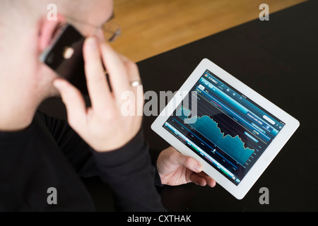 L'uomo controllo prestazioni del FTSE borsa i dati sull'iPad3 computer tablet Foto Stock