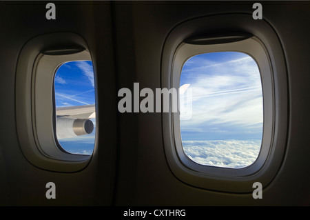 Vista orizzontale attraverso una finestra di aeroplano di cumulus e stratocumulus nuvole e sentieri di vapore attraverso il cielo. Foto Stock