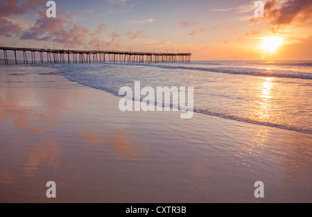 Cape Hatteras National Seashore, Avon, North Carolina Sunrise e riflessioni sulla spiaggia con Avon pesca del molo a distanza Foto Stock