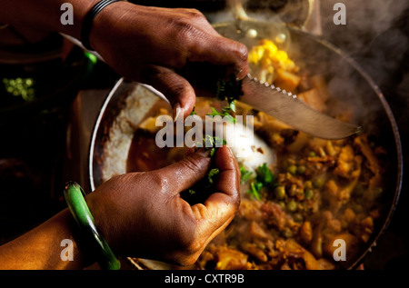 Un cuoco trita erbe in questa padella di cottura sulla parte superiore di una stufa in questa cucina in Dehradun, India. Foto Stock