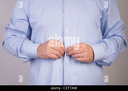 L'uomo abbottonatura suo shirt Foto Stock