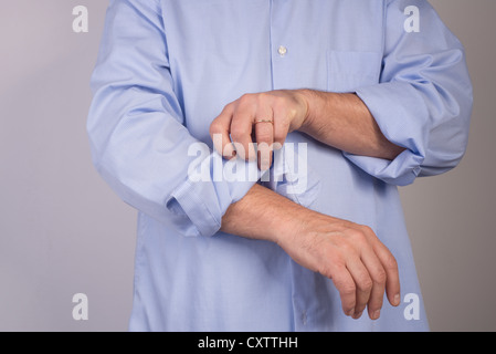 Uomo che arrotola la sua maglietta maniche Foto Stock