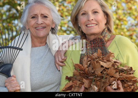 Due donne a rastrellare foglie Foto Stock