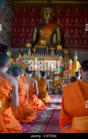 I monaci buddisti si impegnano nella preghiera al Wat Mahathat a Luang Prabang, Laos Foto Stock