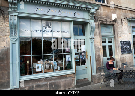 Una donna seduta al di fuori delle belle Cheese Company su Walcot Street nella città di Bath, Avon, Somerset, Inghilterra KATHY DEWITT Foto Stock