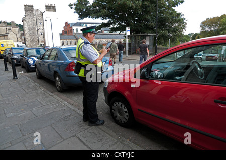 Una femmina di parcheggio attendant di emettere un biglietto di penalizzazione sul Walcot Street in Bath Spa, Avon, Somerset, Inghilterra, Regno Unito KATHY DEWITT Foto Stock