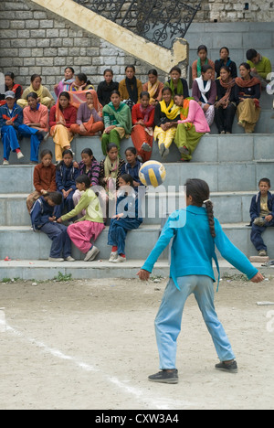 Una ragazza serve la sfera in una ragazza partita di pallavolo in Keylong, India del Nord Foto Stock