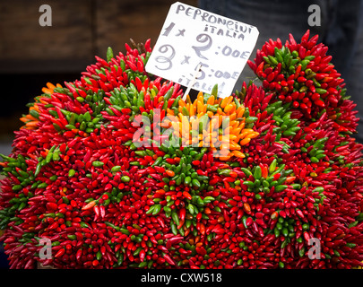 I grappoli di rosso, verde e giallo il peperoncino in vendita su un mercato in stallo a Venezia. Foto Stock