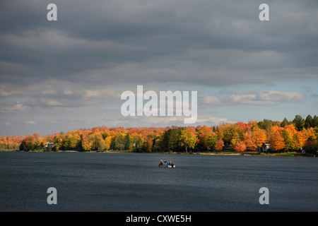 I pescatori in una barca sul Lago di Eugenia con Sun su rosso acero sulla riva in autunno Beaver river valley Ontario Canada Foto Stock