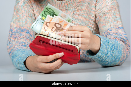 Elevato valore nominale delle banconote in euro in una donna di mano che trattiene un rosso portafoglio in pelle Foto Stock
