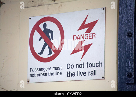 I passeggeri non devono attraversare la linea e il pericolo non toccare la rampa dal vivo segno alla stazione ferroviaria Foto Stock