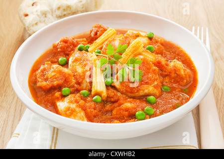 Stufato di pollo con i pomodori e i piselli e il mais per bambini serviti con pane morbido. Foto Stock