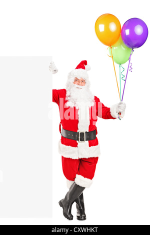 A piena lunghezza Ritratto di un felice santa claus in piedi accanto ad uno sbozzato billboard e palloncini di contenimento isolato su bianco Foto Stock