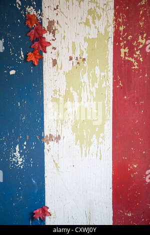 Vintage fienile con legno scheggiato patriottica strisce dipinte su vernice verde con colorate cadono le foglie. Foto Stock
