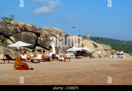 Gli stranieri womens godendo di prendere il sole vicino scogliera sulla località di villeggiatura di Chowara Beach South Kovalam in Kerala India Foto Stock