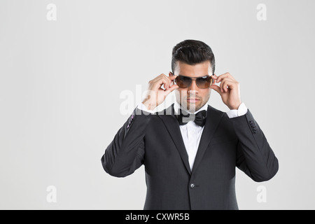 Uomo in smoking regolando i suoi occhiali da sole Foto Stock