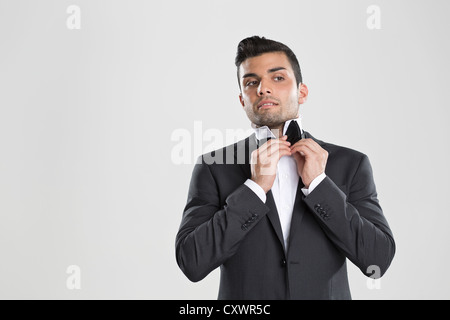 Uomo in smoking regolando il suo bow tie Foto Stock