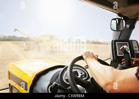 Agricoltore trebbiatrice guida in campo di coltivazione Foto Stock