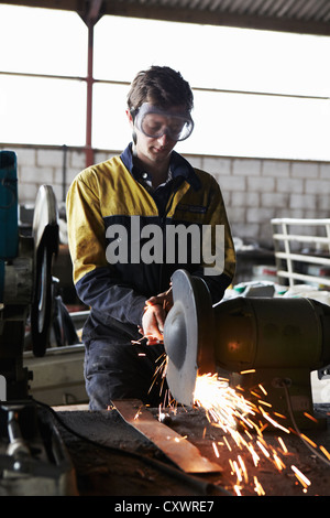 Lavoratore di metallo utilizzando mola in negozio Foto Stock