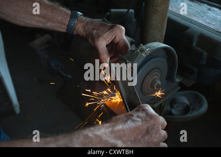 L'uomo l'affilatura del coltello in macchina negozio Foto Stock