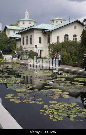 Guardando attraverso il giglio di piscine con il classico edificio amministrativo nella parte posteriore al Brooklyn Botanic Garden, Brooklyn, New York. Foto Stock