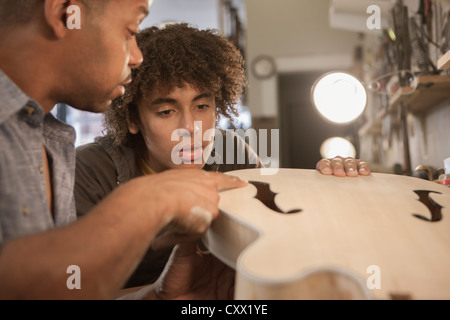 Padre spiegando la costruzione della chitarra al figlio Foto Stock